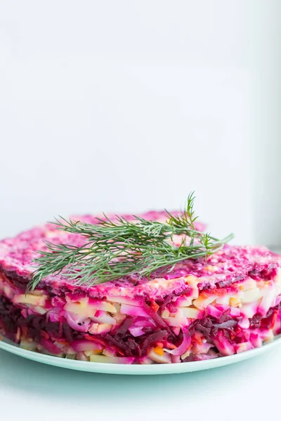 Russischer Salat, Hering im Pelzmantel. traditioneller Heringssalat mit Roter Bete, Karotte, Eiern, Kartoffeln und Rüben auf Keramikteller .Feiertagssalat der russischen Küche. — Stockfoto