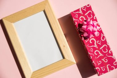 Boş ahşap çerçeveli, hediye kutulu, pembe arka planlı Sevgililer Günün kutlu olsun. Sevgililer günü, anneler günü, evlilik yıldönümü konsepti. Kopyalama alanı ile en üstteki görünüm. En düşük düzlem biçimi