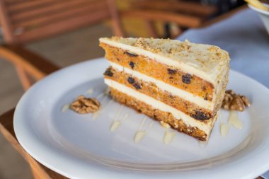 Beyaz tabakta cevizli havuçlu kek. Çiğ vegan ve fındıklı glütensiz havuçlu kek. Sağlıklı ev yapımı tatlı. Seçici odak