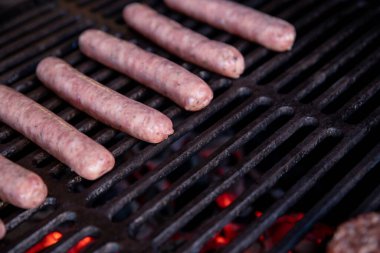Yaz pikniğinde mangalda pişen çiğ domuz sosisi, ızgaranın, etin ve ateşin kapağı. Çayırda duman ve alevle ızgara sosis. Barbekü pikniği. Seçmeli odak