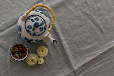 Üst görünüm atış bitkisel çay beyaz ve mavi seramik kupa ve çaydanlık gri keten masa örtüsü olarak görev yaptı. Yatay atış ve negatif boşluk.