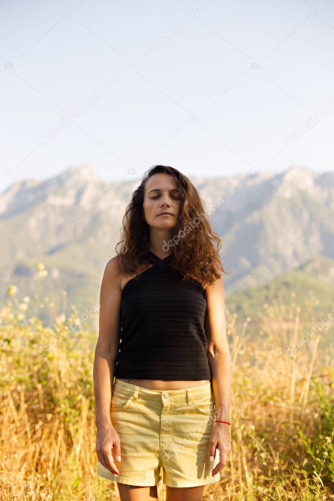 Female with eyes closed with mountains in the background