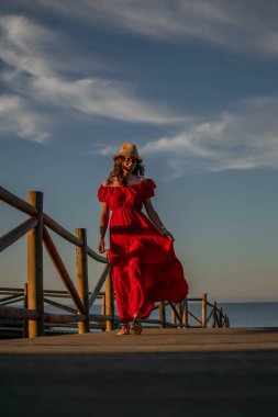 Kırmızı elbiseli bir kadın model, kameraya doğru yürüyordu.