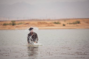 Fas'ta Erg Cheggaga kumlu kumulları arasında gölde duran Arap tarzı bornoz adam 