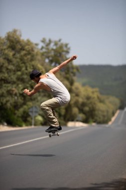 sunny gün yolda aşağı paten sürme sırasında atlama hile performans sokak kıyafeti kaykaycı