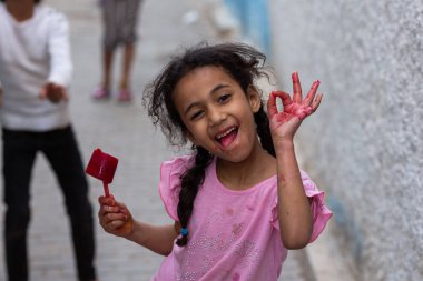  dondurma tutan ve eski sokakta kamera ok işareti gösteren sevimli küçük faslı esmer kız portresi, Fez, Fas   
