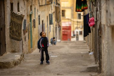 güneşli bir günde eski mahalledar sokakta yürüyen küçük çocuk, Fez, Fas