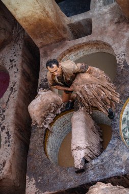 adam deri şekilleri tutan ve Fes deri tabakhanelerde boya potçok çalışıyor, Fas