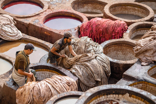workers tinting leather in traditional way at old tannery in Fes, Morocco 