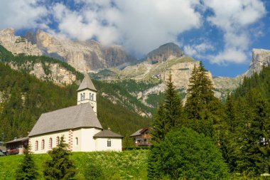 Moena 'dan Canazei, Trento, Trentino Alto Adige, İtalya' ya kadar Fassa Vadisi 'nin bisiklet yolu boyunca Dolomitlerin dağ manzarası. Kilise