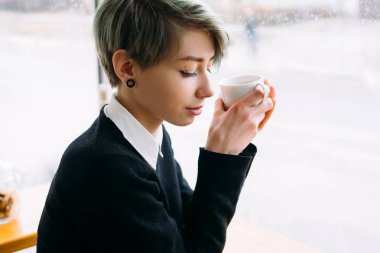 Genç kadın sit kafe tutun fincan kahve eğlence