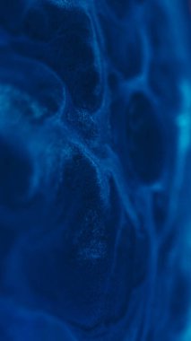 Mürekkep taneleri. Parlak sıvı. Bulanık mavi renk su dokusu toz köpüren karışım soyut yaratıcı akrilik sanat arka planına yayılıyor.