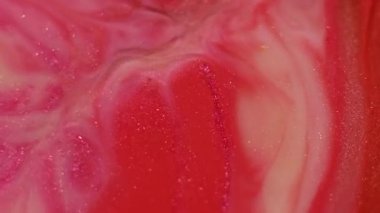 Parlak akışkan sıvı. Soyut mürekkep. Odaklanmamış kırmızı, mor renkli su parıltılı sıvı parçacıkları sanatın canlı arka planına dökülüyor..