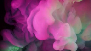Duman akışı. Neon mürekkebi. Pembe yeşil dumanlı patlama. Sanat sıvısında karışan kıvrımlı kıvrımlı renk. Siyah sıvı soyutlanmış arkaplan.