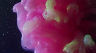 Sis sıvısı. Parıldayan dalga. Neon parlak boya sisi suda çözülüyor. Siyah arkaplan parlaklığında pembe yeşil duman soyut bulanık karışımı.