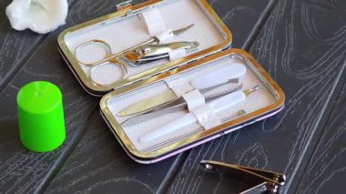 Tırnak makası, makas, tırnak törpüsü ve tırnak törpüsü ile manikür seti, koyu ahşap bir yüzey üzerinde yeşil bir kozmetik kap ve pamuk pedlerin yanında.