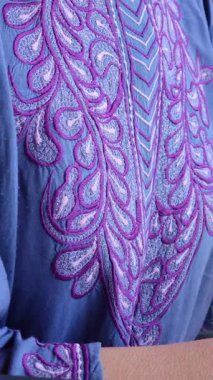 Detaylı pembe nakış, mavi kumaş süsleme, zarif dikiş ve kültürel tekstil sanatları sergileniyor.