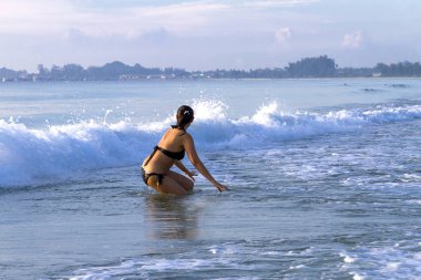 Woman with black bikini play on wave at beach 