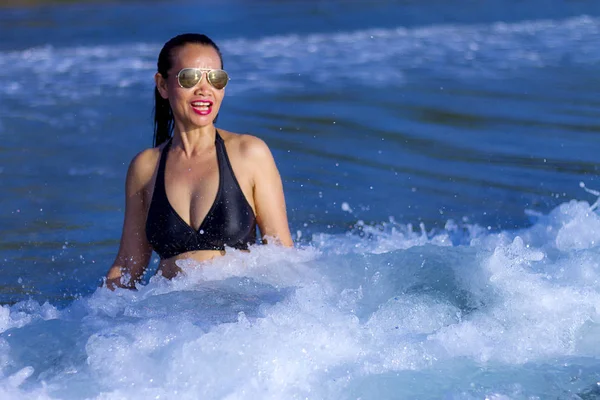 Woman with black bikini happy with wave on beach — 스톡 사진