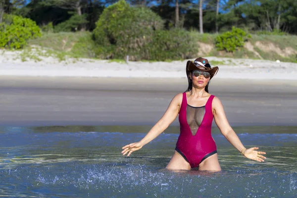 Woman bikini crimson and hat play wave on beach — Stok fotoğraf