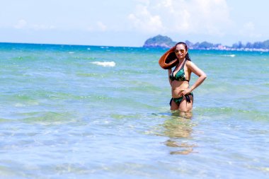 Woman with hat and bikini stand in sea water