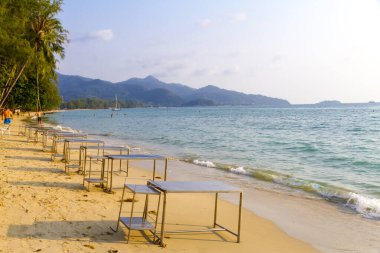 Gezgin ve ailesi Koh Chang Tayland sahilinde güneş ışığıyla yürüyor.