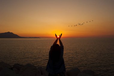gün batımı sırasında genişletilmiş elleri ile kadın silüeti.