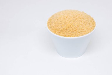 Beyaz arka planda beyaz bardakta kahverengi şeker