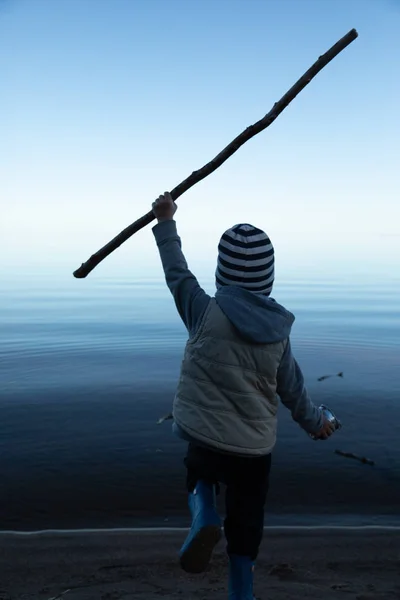 Il ragazzo corre in acqua con un bastone — Foto Stock