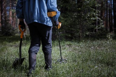 ormanda bir metal detektörü olan bir adam