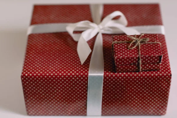 Red gift box with white ribbon on blurred background — Stock Photo, Image