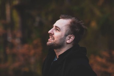 Yan görünüm gülümseyen emin olgun adam. ormanda ararken.