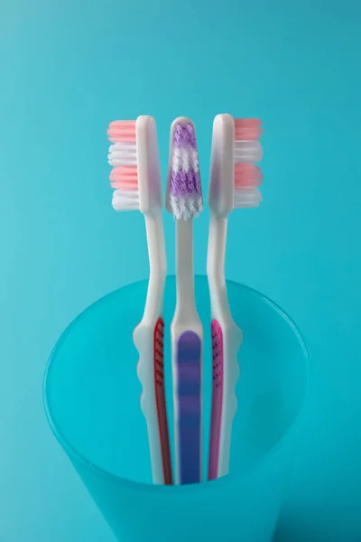 Toothbrushes on a blue background in a blue glass — Stock Photo, Image