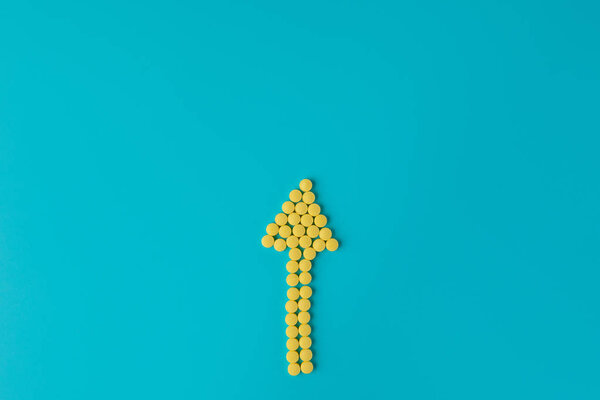 Arrow of yellow pills on a blue background. Flat lay, Top view,