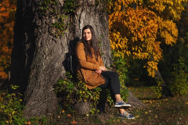 Retrato de una joven mujer de estilo urbano, sentada en el parque. Temporada de otoño . — Foto de Stock