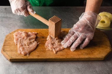 aşçı tavuk ahşap kesme tahtası, eller, tavuk, ananas, eldiven hazırlar. et sirke. peynir ve ananas tavuk fileto tarifi. mutfak masasında üstten görünüm