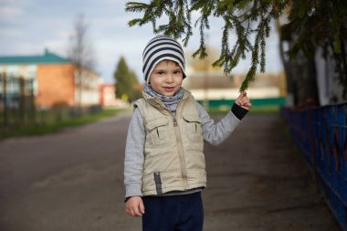 Noel ağacı tutan güzel küçük gülümseyen çocuk çocuk. bir şeritli şapkalı çocuk