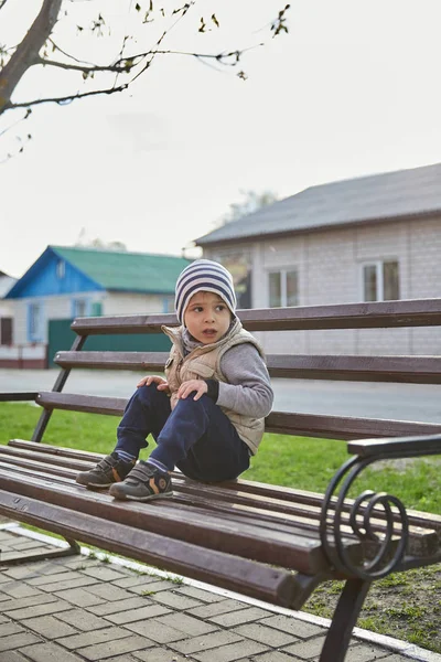 Mały chłopiec siedzi na ławce. dziecko samodzielnie w mieście — Zdjęcie stockowe