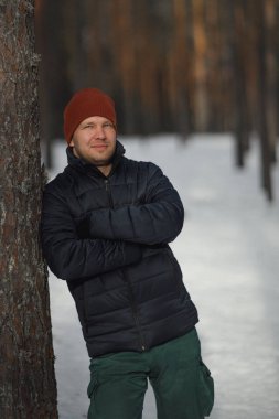 Adam kış manzara içinde. Bir adam bir ceket ve şapkayla bir çam ormanı.