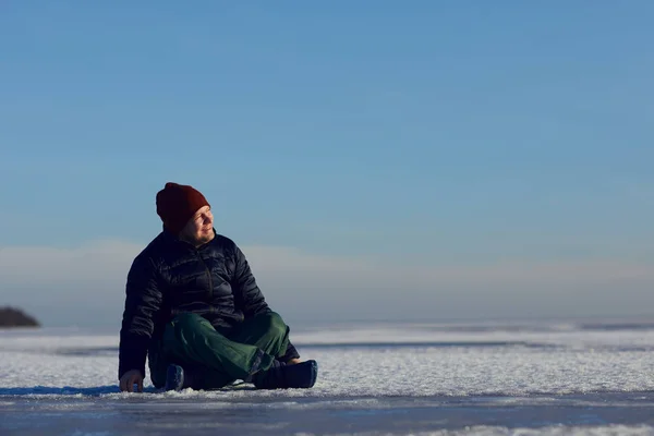 Voyageur assis dans la neige et souriant en regardant le soleil — Photo