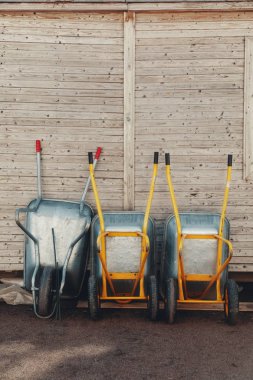 Üç boş bahçe arabası, araba. Ahşap çit karşı eğilerek komik demir bahçe arabalar