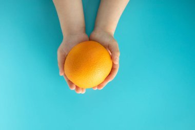 Bir çocuğun elinde mavi arka plan turuncu. Sağlıklı beslenme konsepti