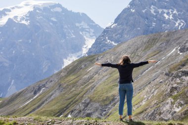 bir hasır şapka kız dağın tepesinde maliyeti ve bulutlar uzak görünüyor.