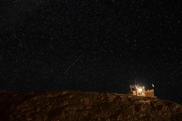 Casa en las montañas por la noche contra el cielo estrellado. castillo en las montañas italianas sobre un fondo de estrellas — Foto de Stock