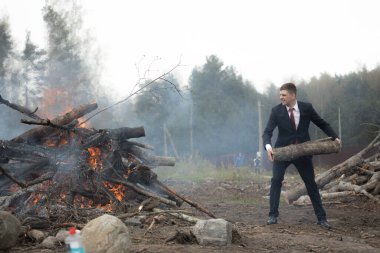 Ateşe odun atmak. Bir adam doğada ateşe odun atar..