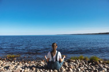 Kız gölün kıyısında yoga yapıyor..