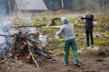 Ustabaşı ve müşteri. Müşteri işçiye ne yapacağını gösterir. Ülkede inşaat atıkları yanıyor..