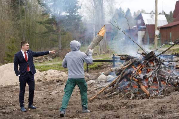 Ustabaşı ve müşteri. Müşteri işçiye ne yapacağını gösterir. Ülkede inşaat atıkları yanıyor..