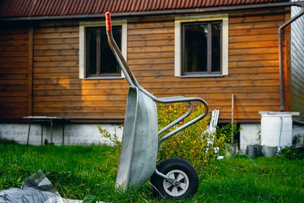 Kolečko v pozadí venkovského domu. Železné auto na venkově. — Stock fotografie