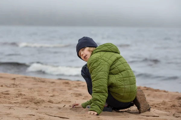 Ritratto di una ragazza in giacca sulla riva. Bambino sulla spiaggia in riva al mare freddo. — Foto Stock